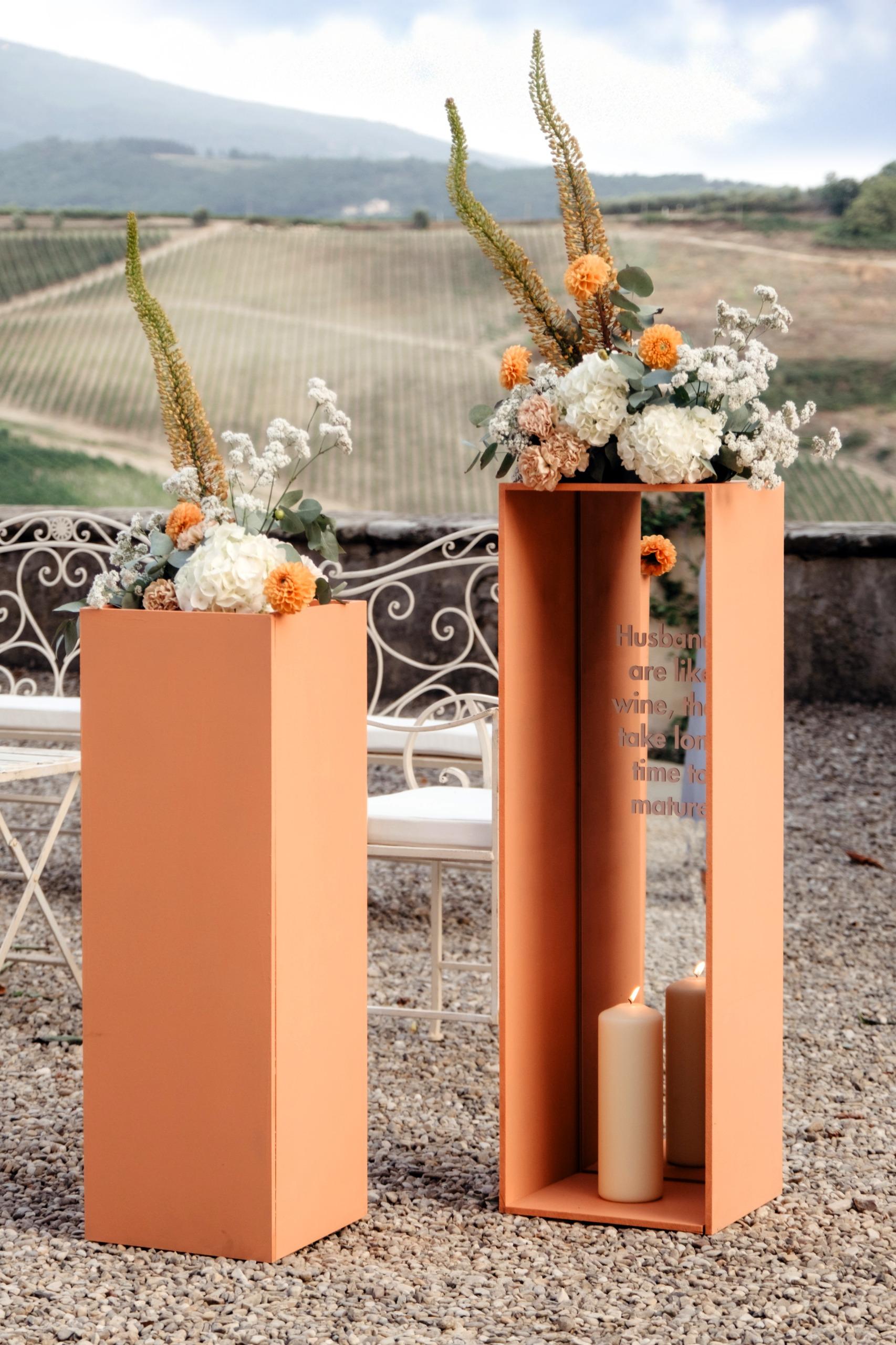 Installazioni floreali su plinti color terracotta, con le colline vitate della Toscana sullo sfondo